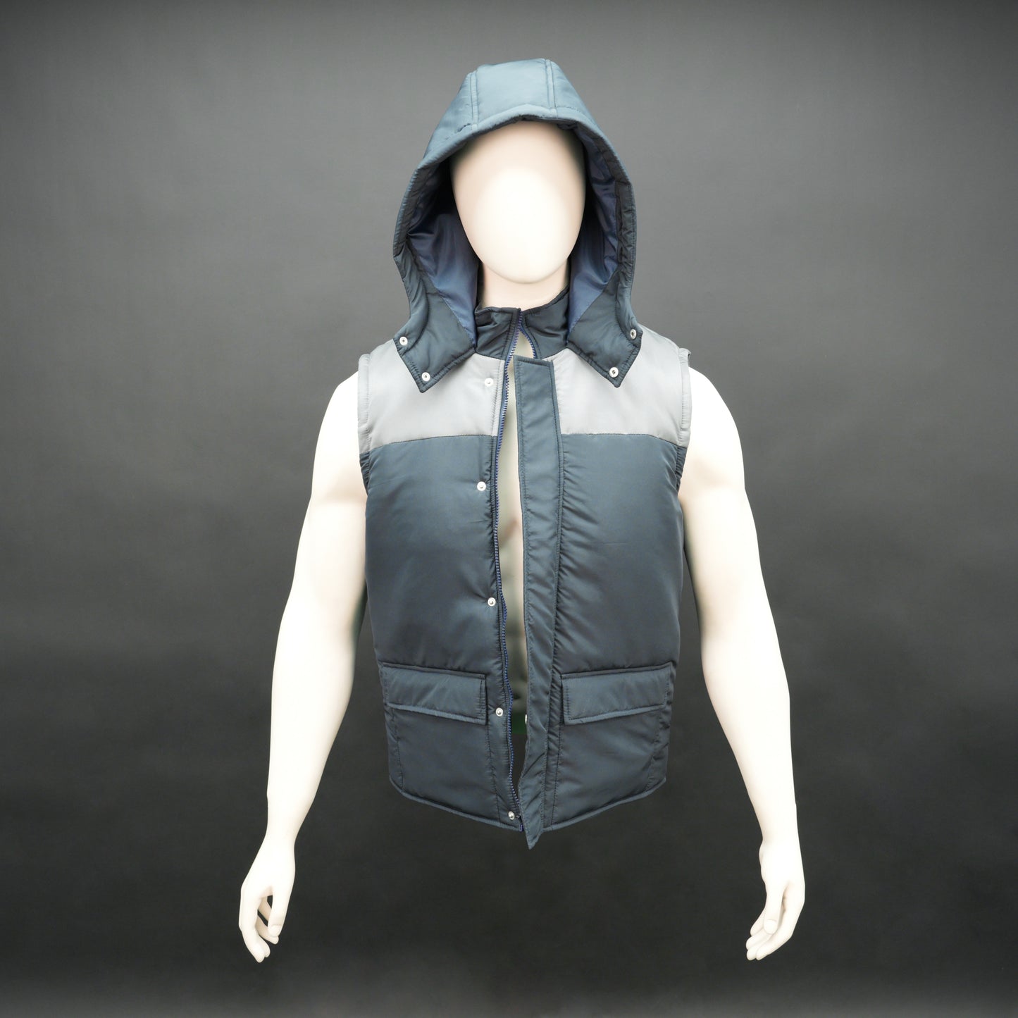 Navy-grey sleeveless puffer jacket with zip and snap closure, hood, side and inner pockets, premium fabric for warmth.