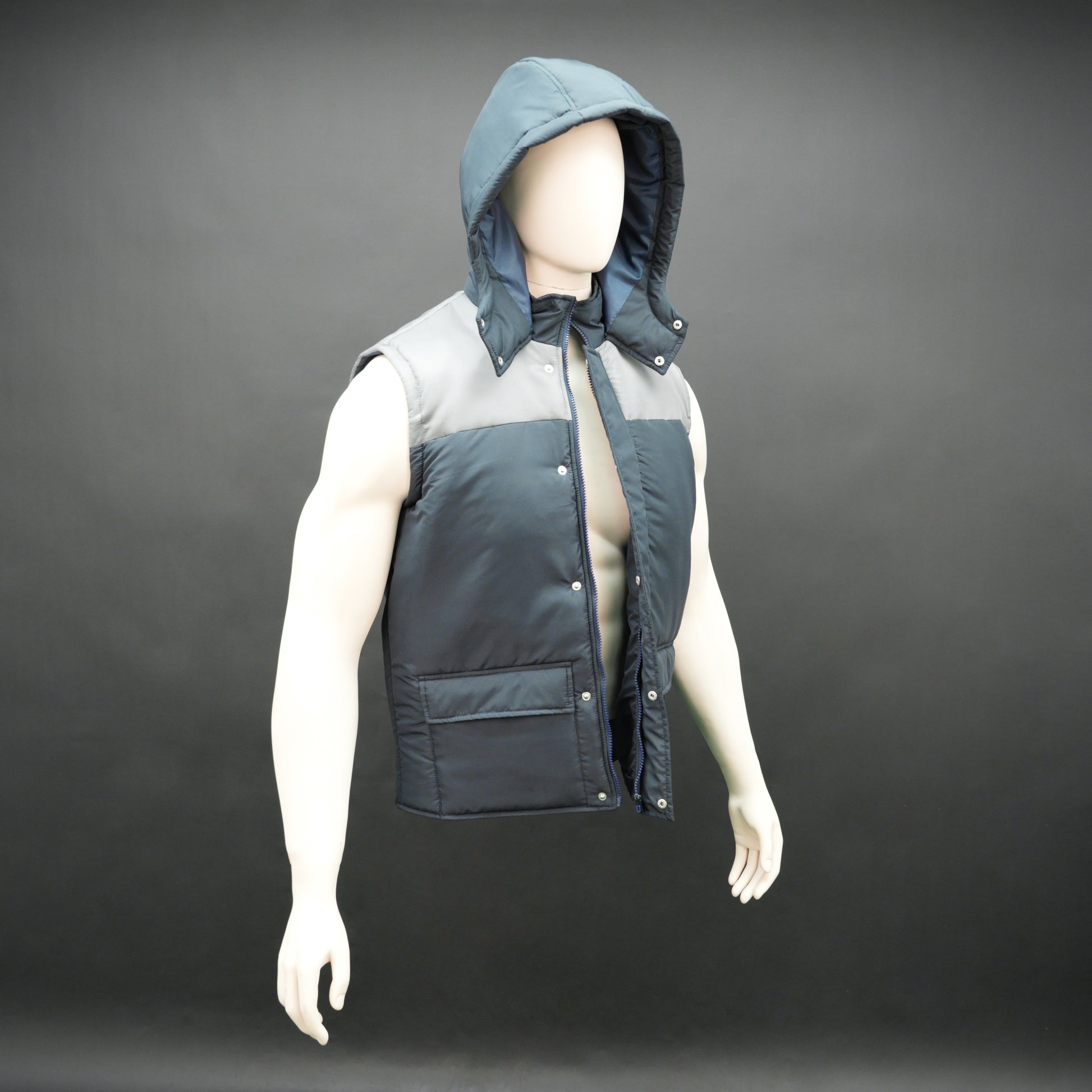 Navy-grey sleeveless puffer jacket with zip and snap closure, hood, side and inner pockets, premium fabric for warmth.