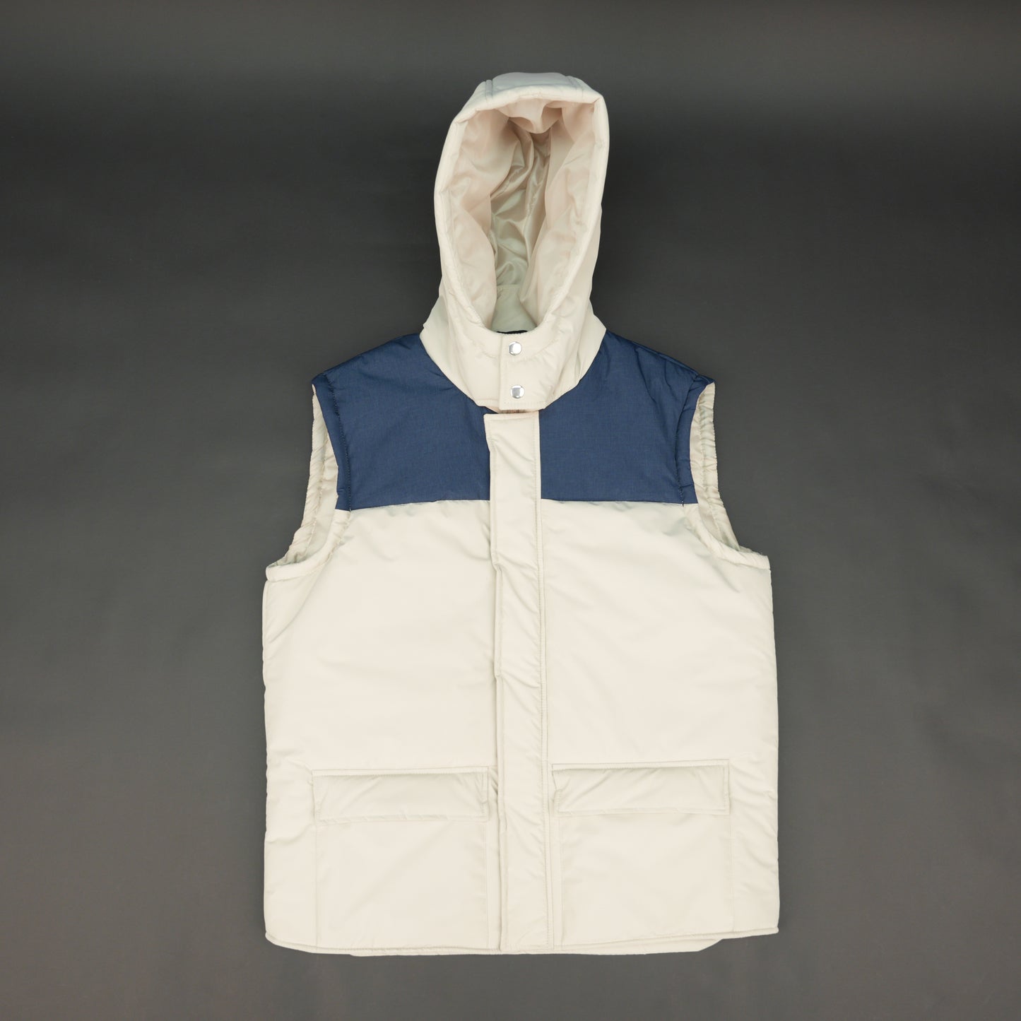 Cream-blue two-tone sleeveless puffer jacket with zip and snap closure, hood, side and inner pockets, quilted for layering