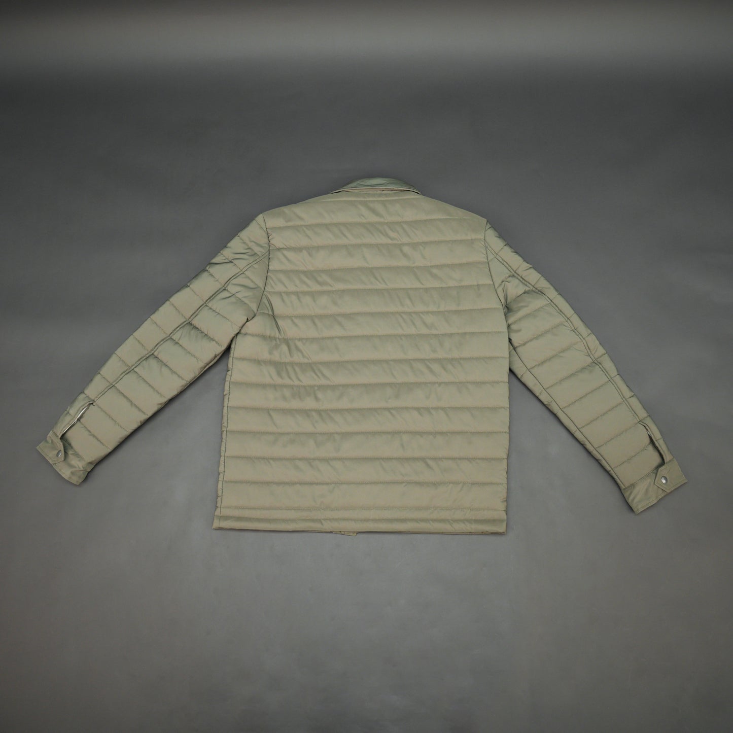 Green full-sleeve puffer jacket with snap closure, quilted padding, inner and outer pockets, designed for everyday comfort.