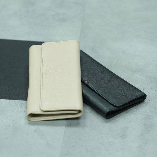 Black and beige genuine leather clutches displayed side by side, both featuring a sleek design with 2 open pockets, 1 zip pocket, and 11 card slots — showcasing elegant style