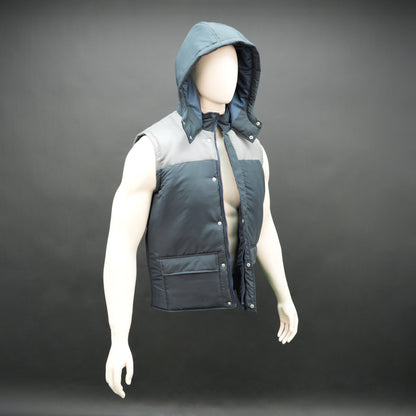 Navy-grey sleeveless puffer jacket with zip and snap closure, hood, side and inner pockets, premium fabric for warmth.