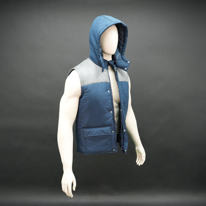 Blue-grey two-tone sleeveless puffer jacket with zip, snap buttons, hood, side and inner pockets, insulated for layering