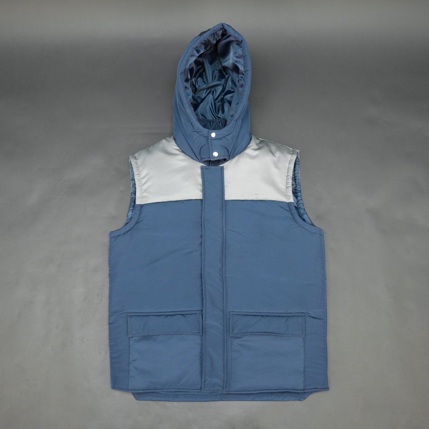 Blue-grey sleeveless two-tone puffer jacket with zip, snap buttons, hood, side and inner pockets, insulated for layering
