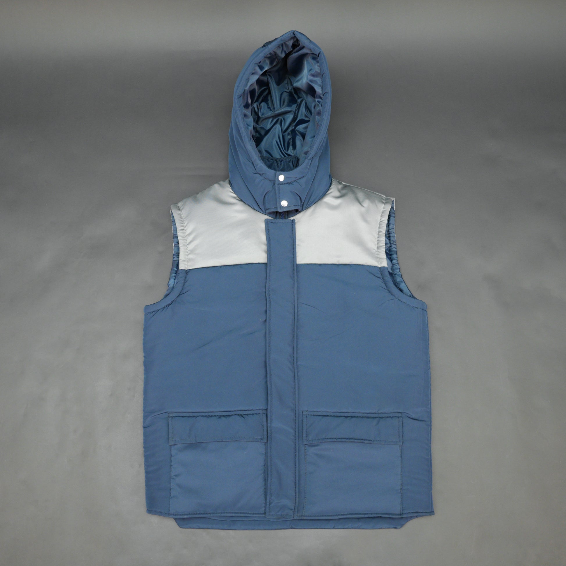 Blue-grey sleeveless two-tone puffer jacket with zip, snap buttons, hood, side and inner pockets, insulated for layering