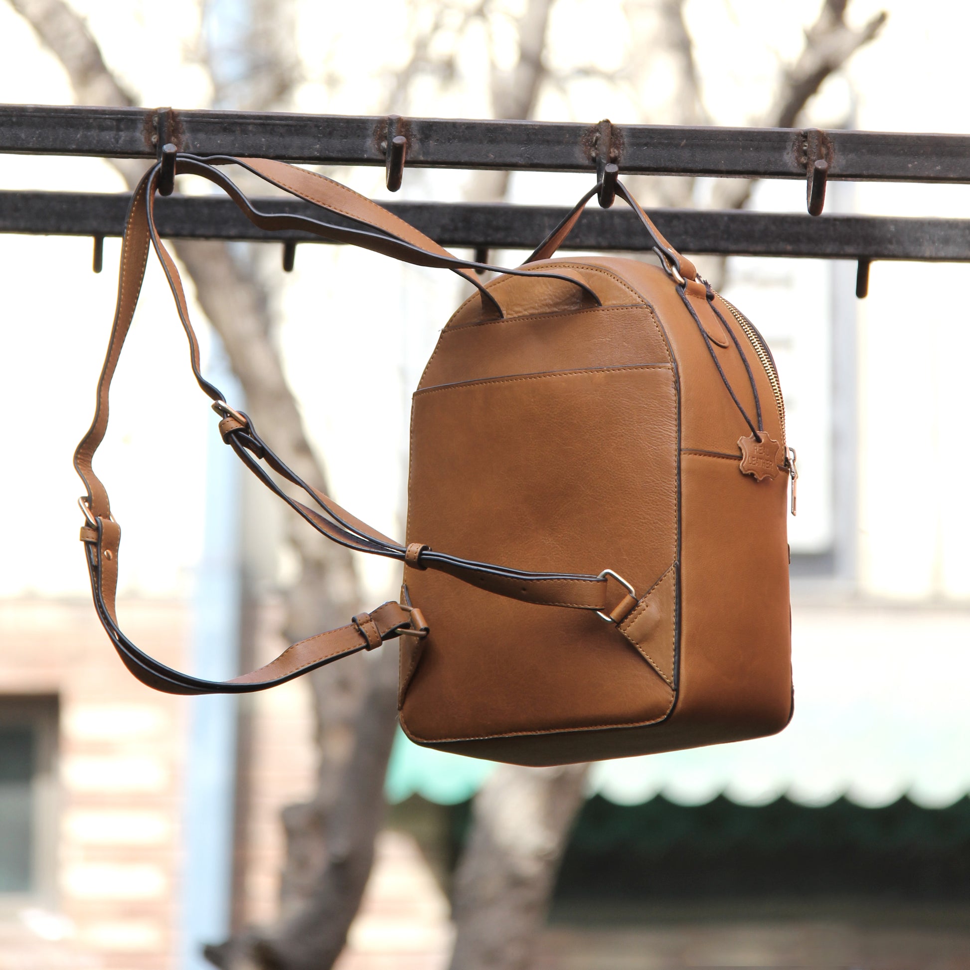 Tan genuine cowhide leather bag with minimalist design, featuring secure closures, spacious interior, and adjustable straps — crafted for durability and style