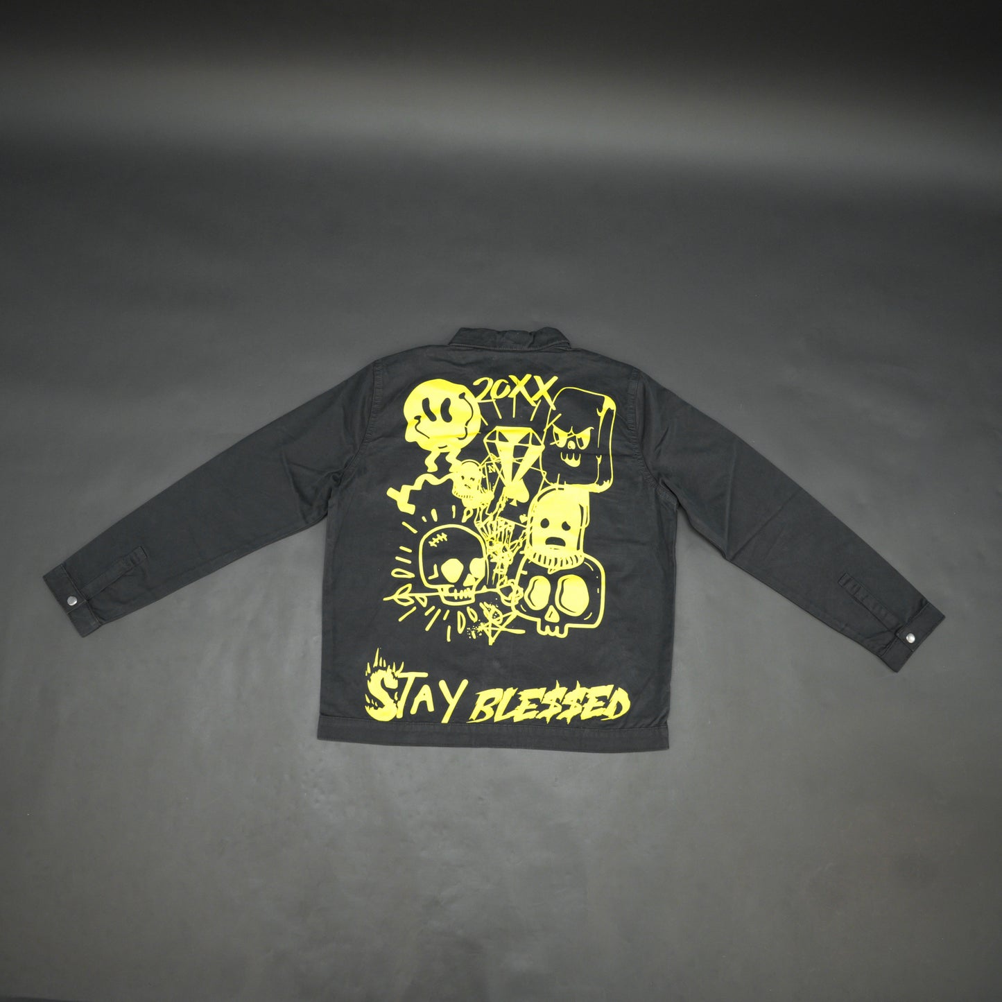 Black denim jacket featuring ‘Stay Blessed’ graphic on the back, button-down front, adjustable cuffs, and side pockets perfect for casual wear