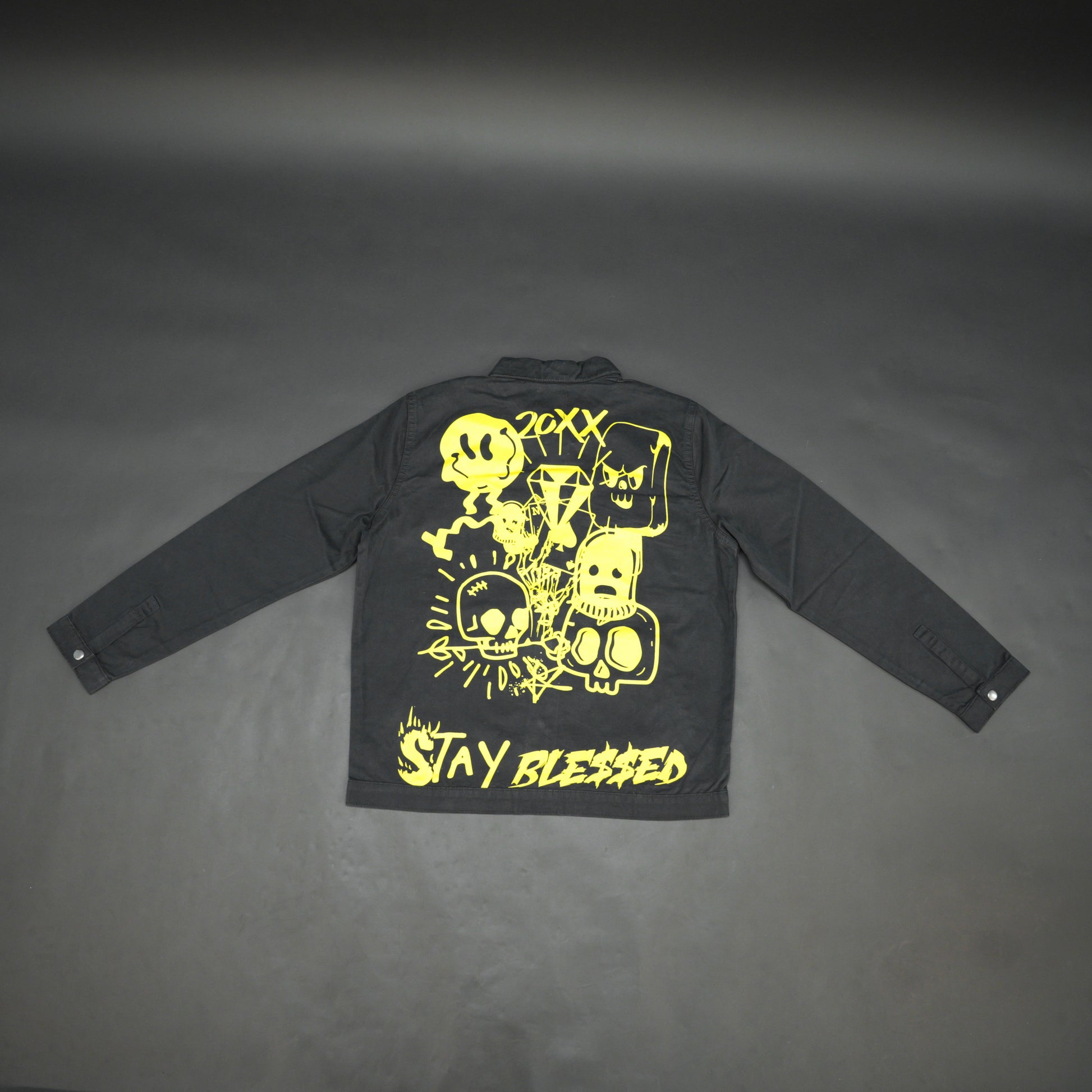 Black denim jacket featuring ‘Stay Blessed’ graphic on the back, button-down front, adjustable cuffs, and side pockets perfect for casual wear