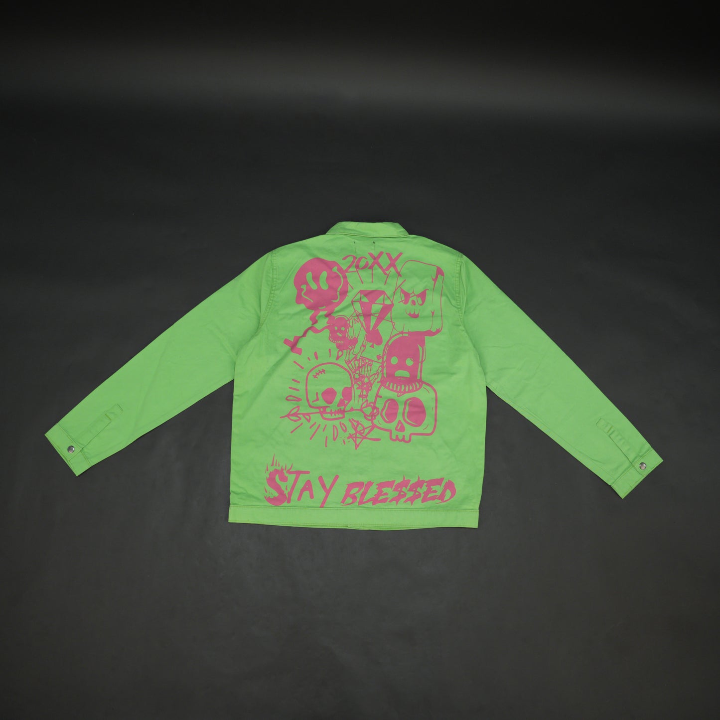 Green denim jacket with bold ‘Stay Blessed’ graphic on the back, button-down front, adjustable cuffs, and side pockets for casual wear