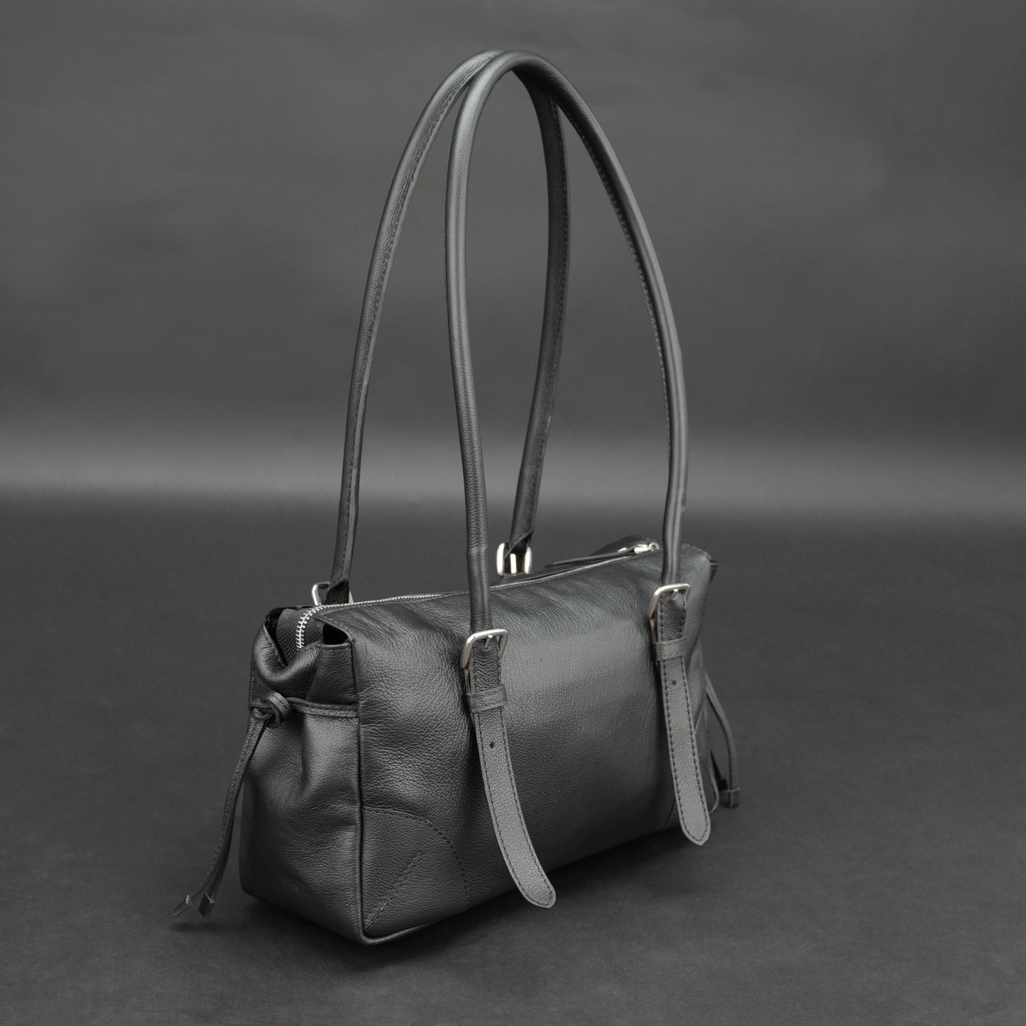 Black cow Chelsea leather bag with strap and pockets.