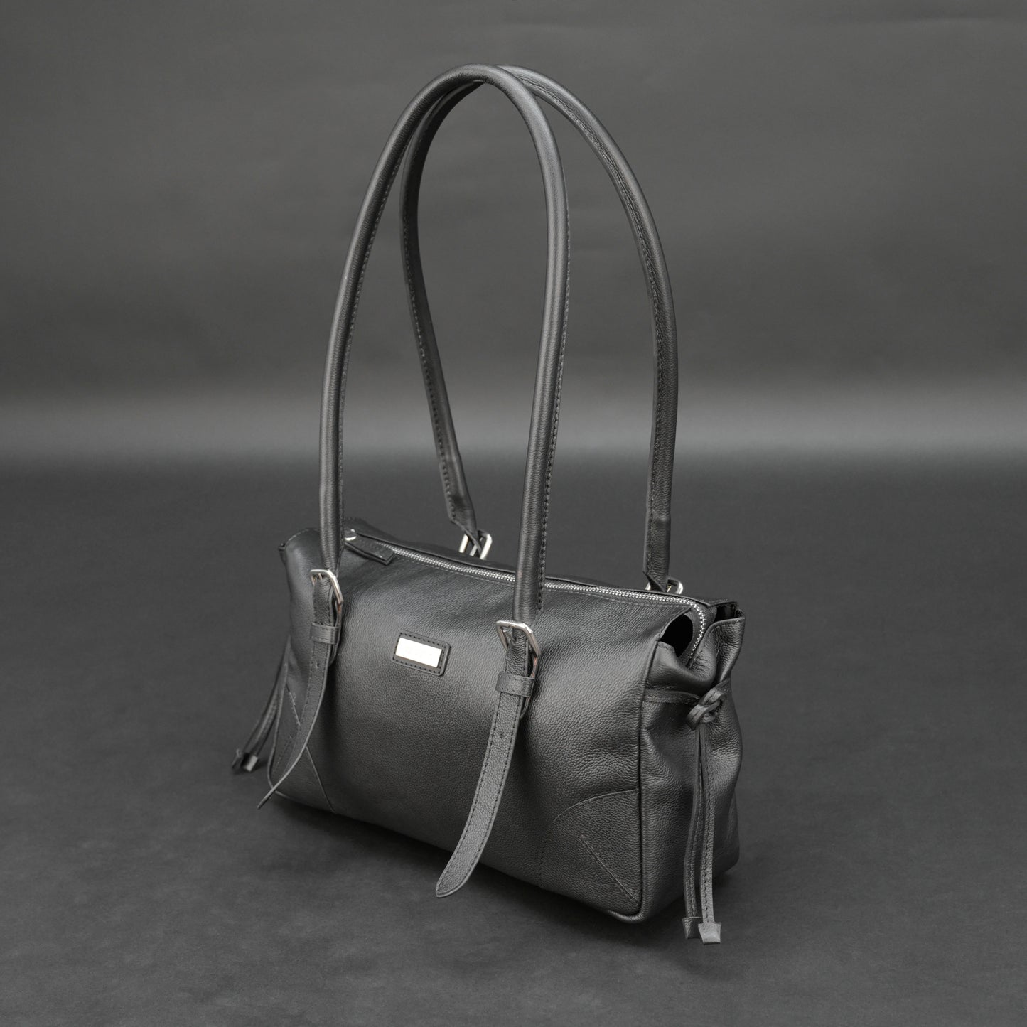 Black cow Chelsea leather bag with strap and pockets.