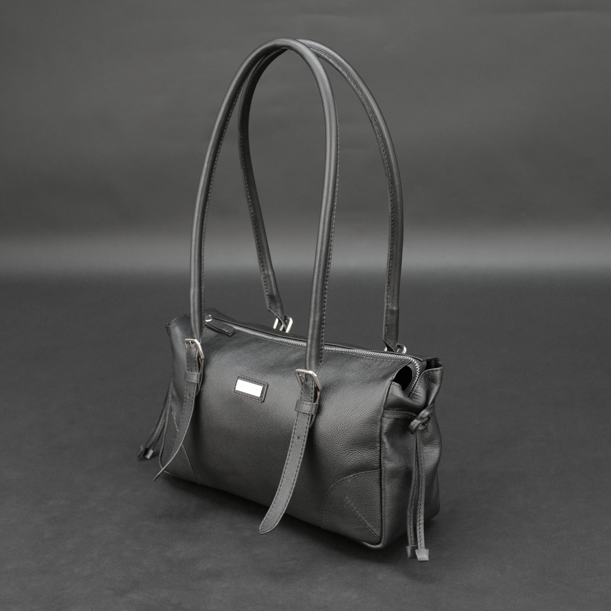 Black cow Chelsea leather bag with strap and pockets.