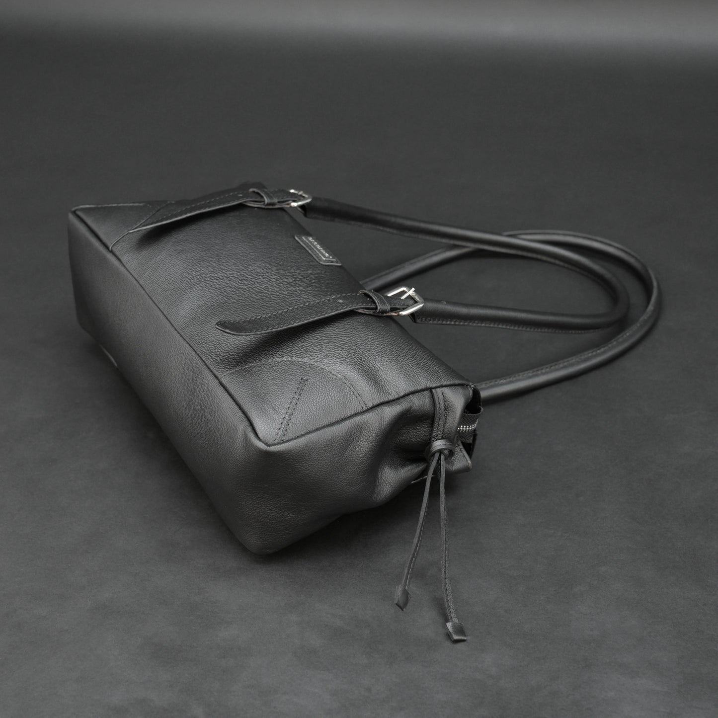 Black cow Chelsea leather bag with strap and pockets.