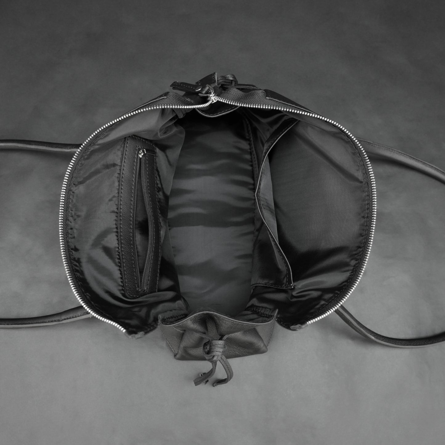 Black cow Chelsea leather bag with strap and pockets.