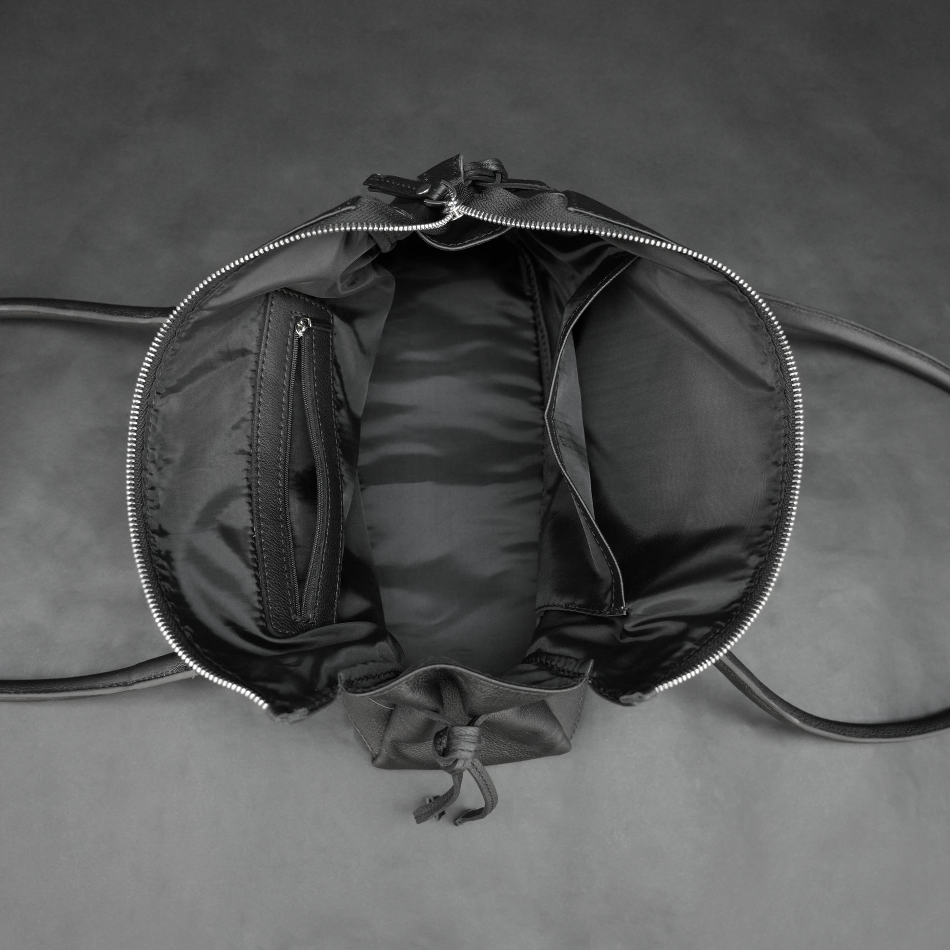 Black cow Chelsea leather bag with strap and pockets.