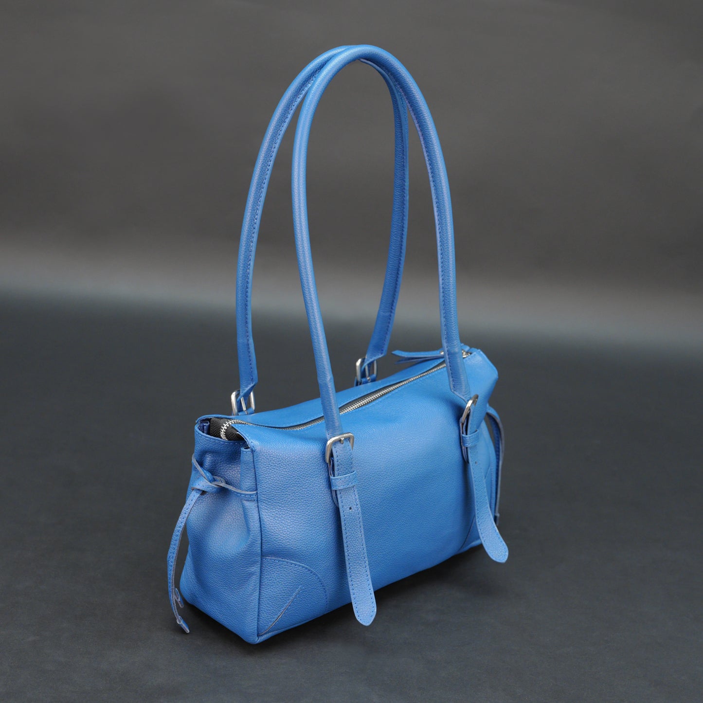 Blue cow PDM leather bag with shoulder strap and pockets.