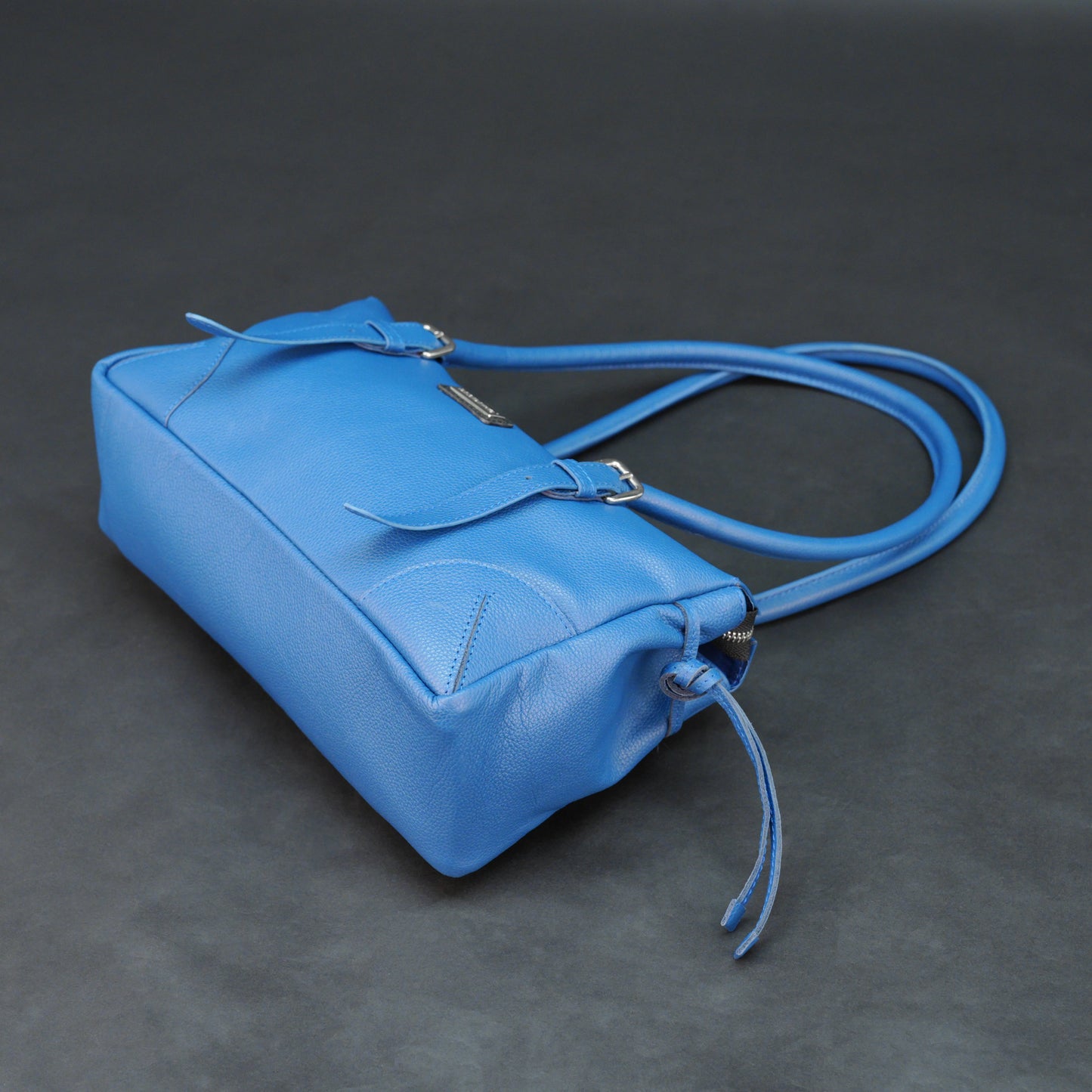 Blue cow PDM leather bag with shoulder strap and pockets.