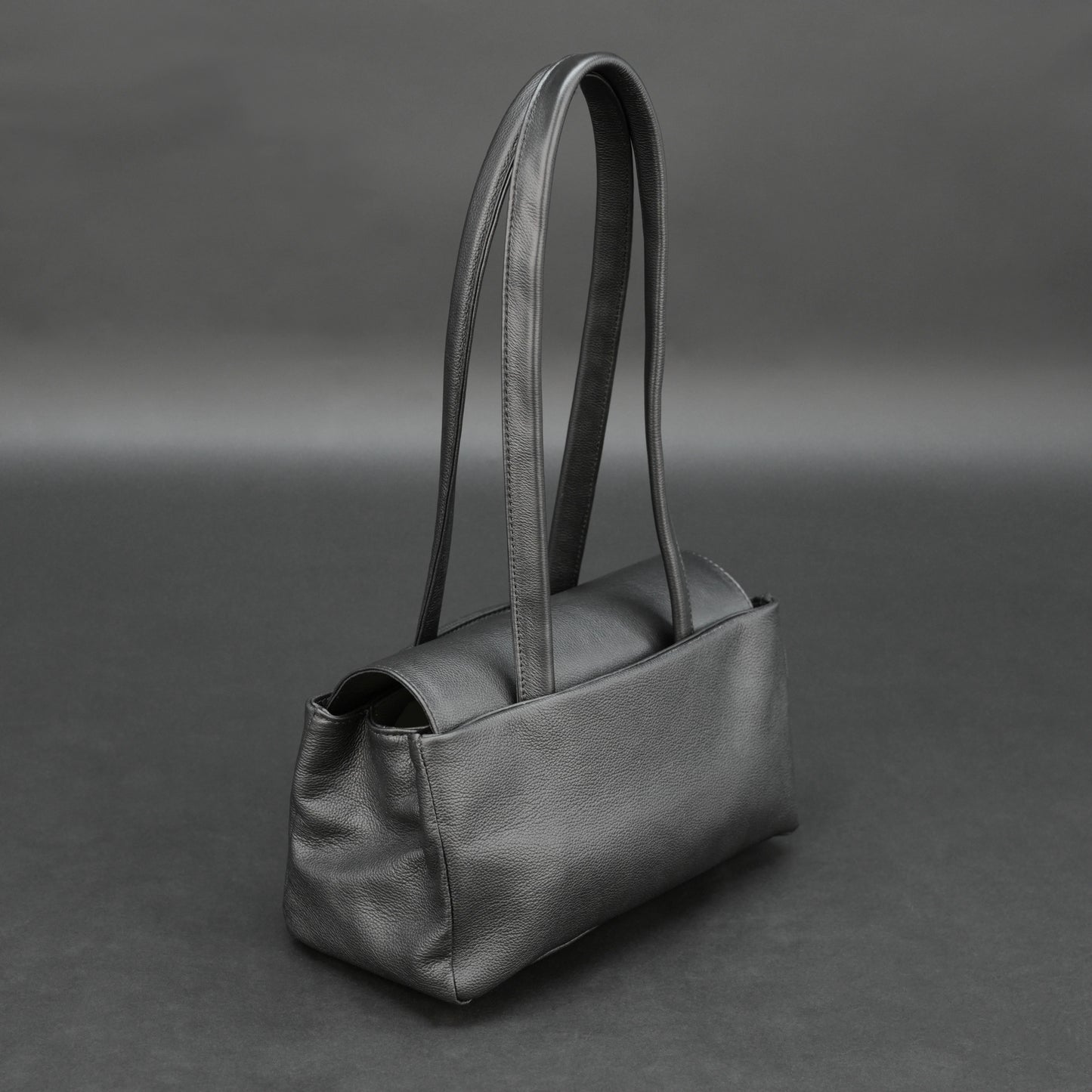 Black cow Chelsea leather bag with straps, compartments, and zipper pocket.