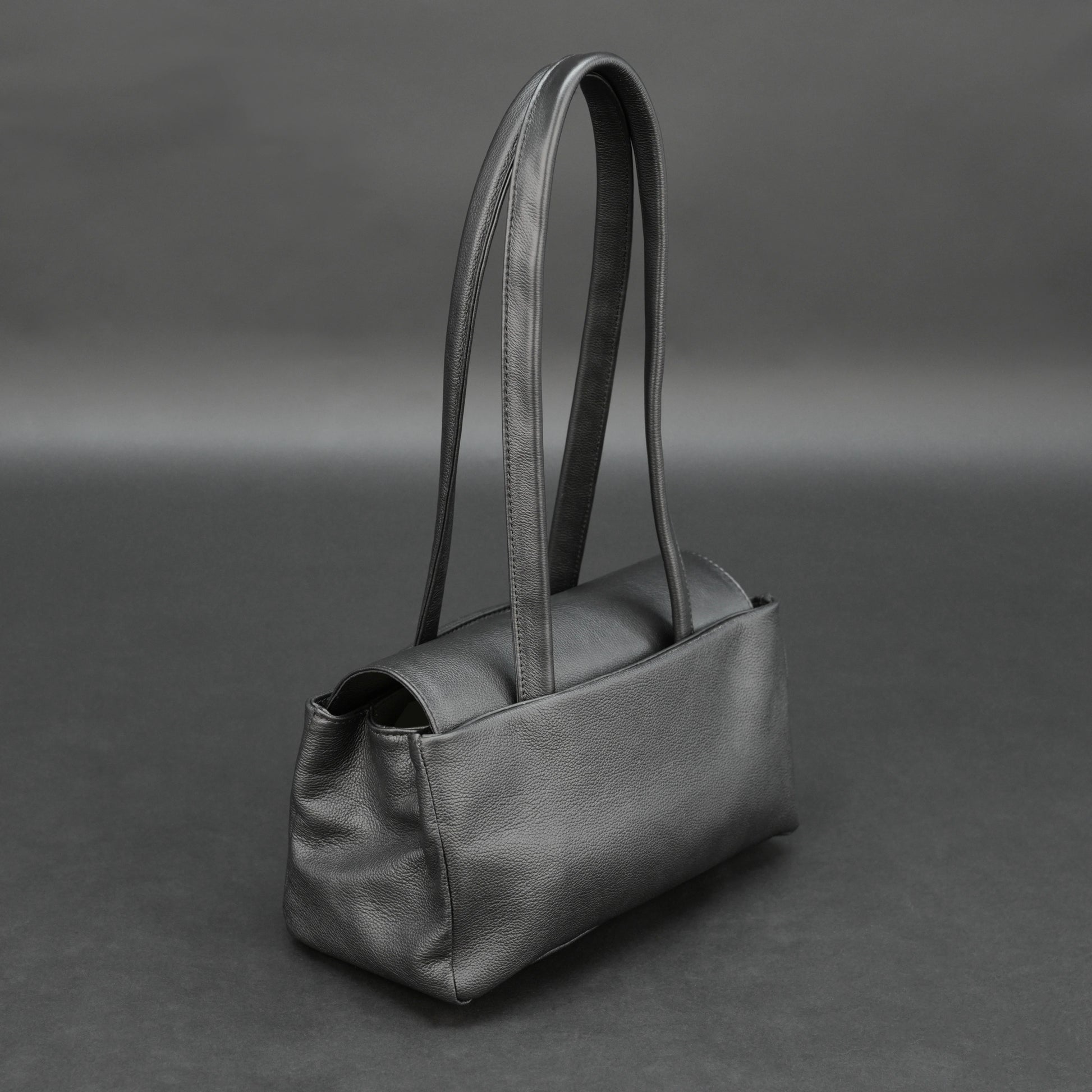 Black cow Chelsea leather bag with straps, compartments, and zipper pocket.