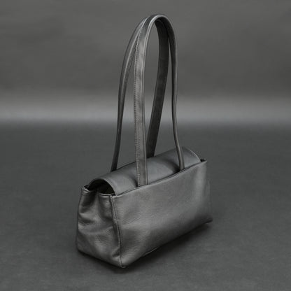 Black cow Chelsea leather bag with straps, compartments, and zipper pocket.