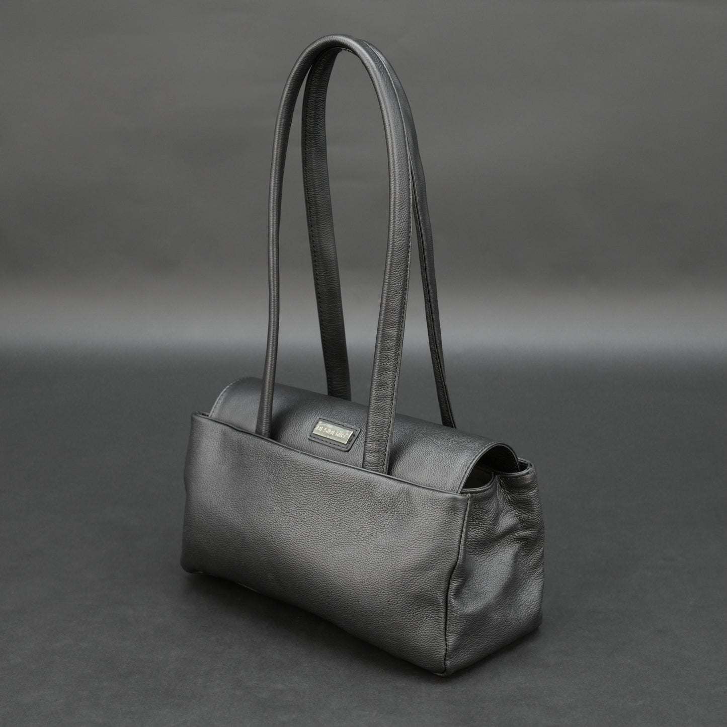 Black cow Chelsea leather bag with straps, compartments, and zipper pocket.