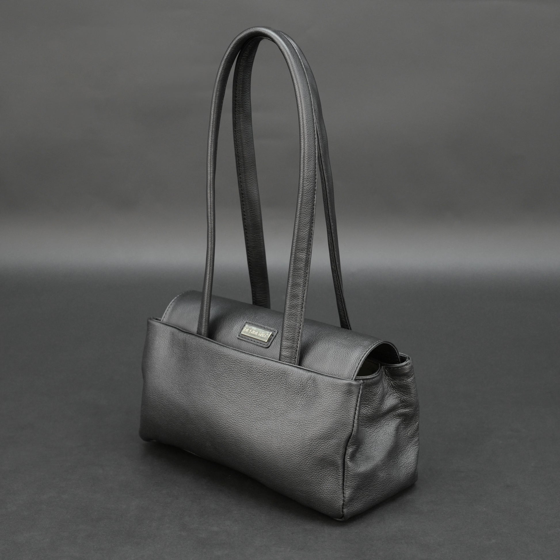 Black cow Chelsea leather bag with straps, compartments, and zipper pocket.