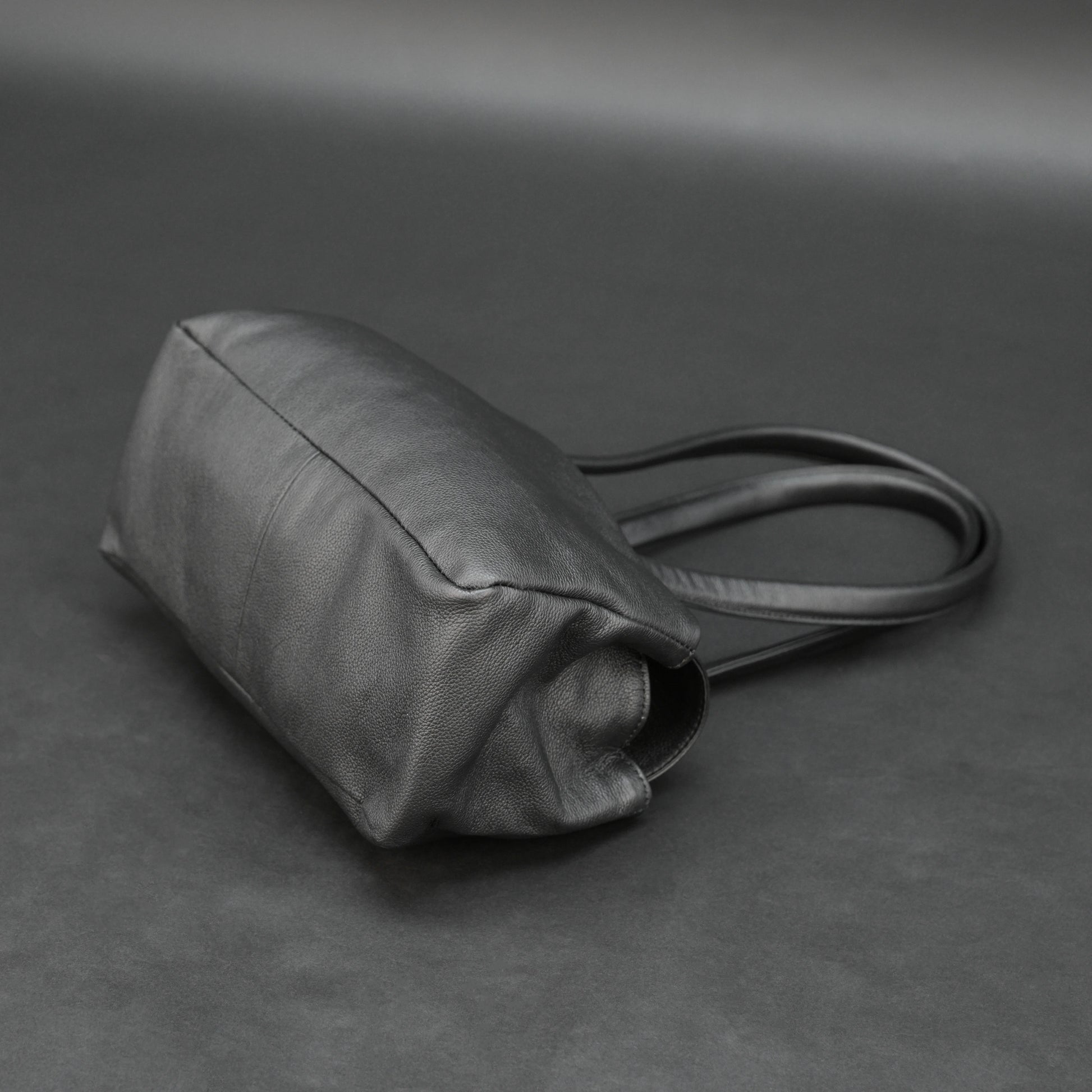 Black cow Chelsea leather bag with straps, compartments, and zipper pocket.