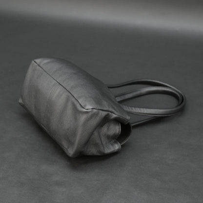 Black cow Chelsea leather bag with straps, compartments, and zipper pocket.