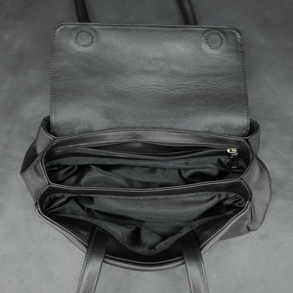 Black cow Chelsea leather bag with straps, compartments, and zipper pocket.