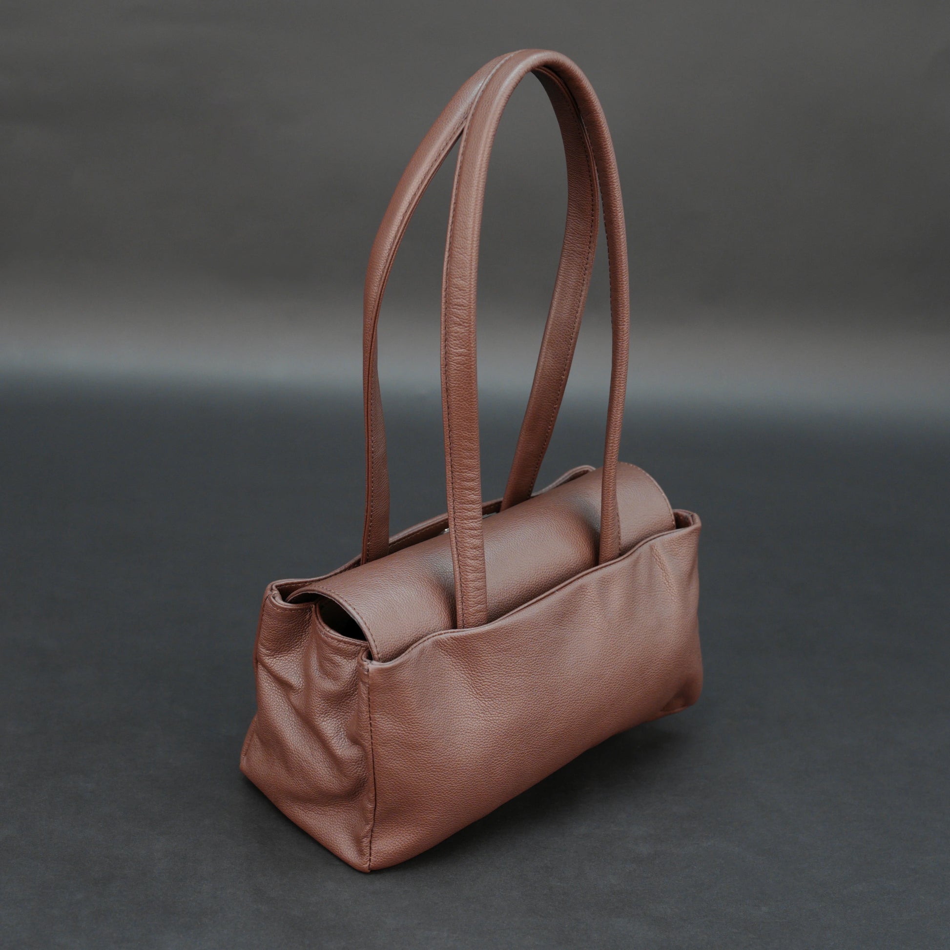 Brown cow Chelsea leather bag with straps, two compartments, and zipper pocket.