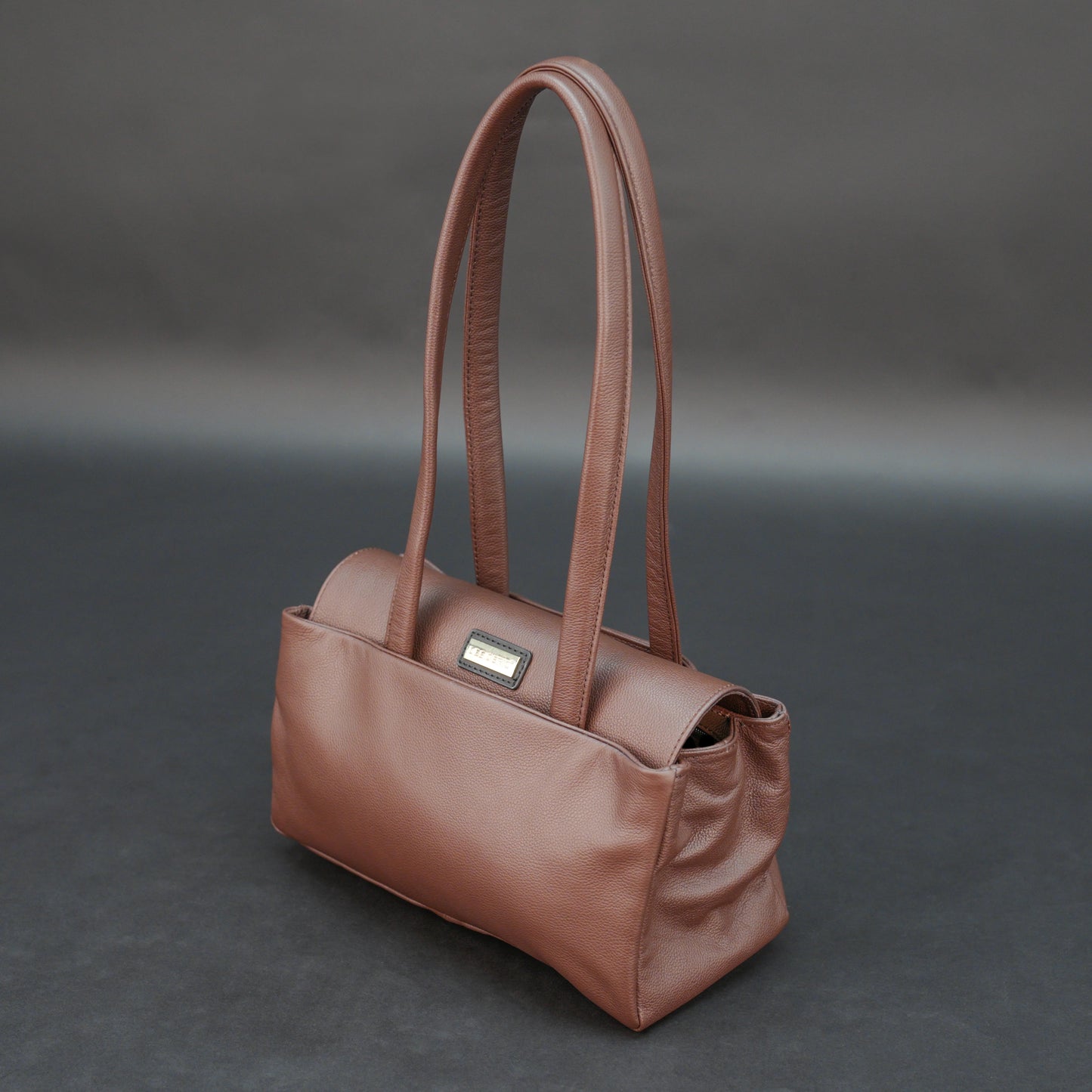 Brown cow Chelsea leather bag with straps, two compartments, and zipper pocket.