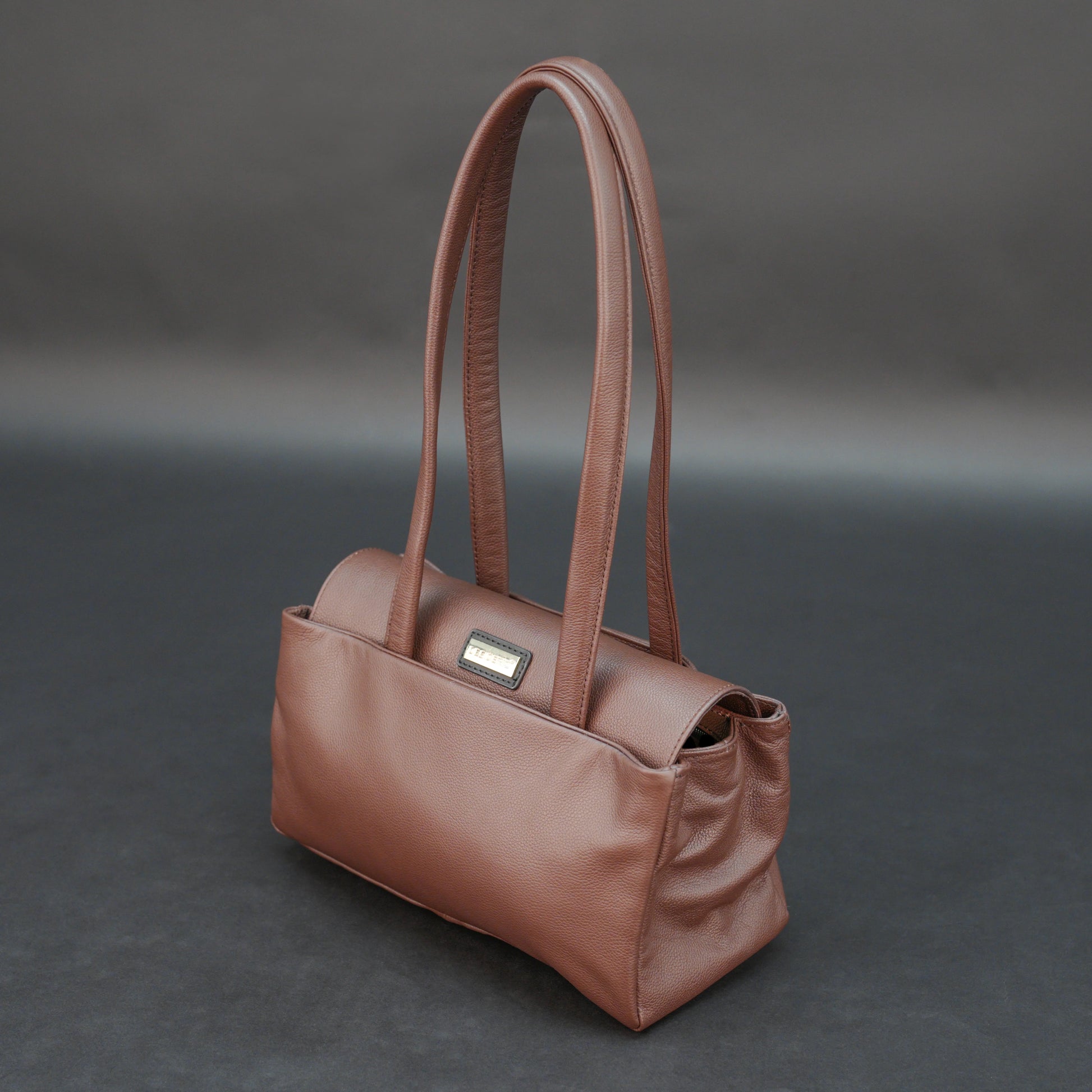 Brown cow Chelsea leather bag with straps, two compartments, and zipper pocket.