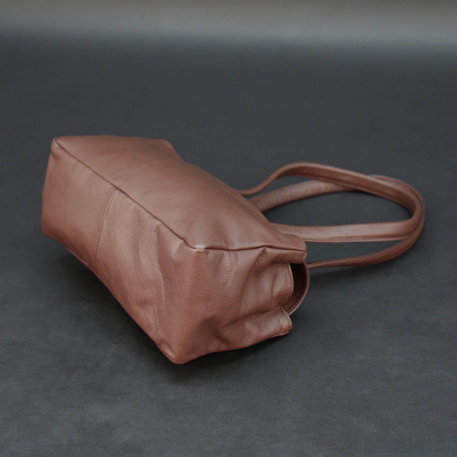 Brown cow Chelsea leather bag with straps, two compartments, and zipper pocket.