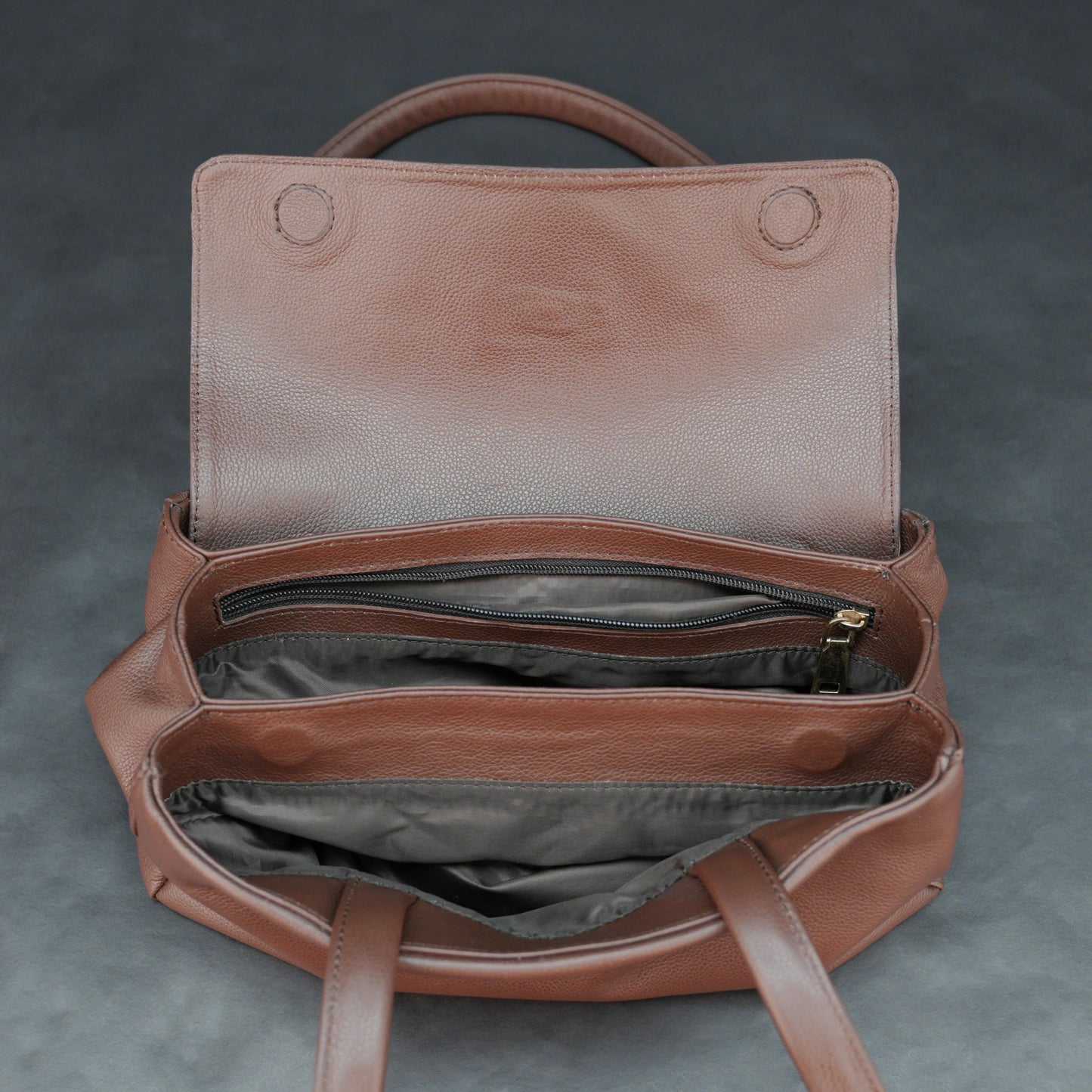 Brown cow Chelsea leather bag with straps, two compartments, and zipper pocket.