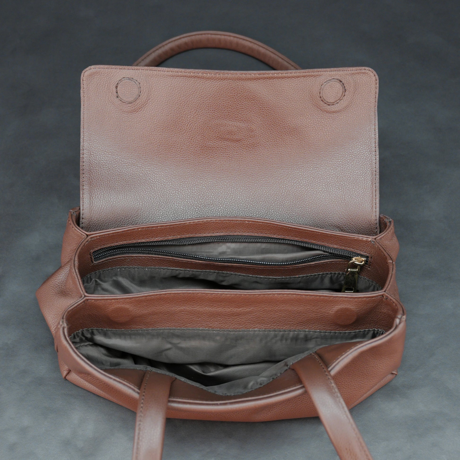 Brown cow Chelsea leather bag with straps, two compartments, and zipper pocket.