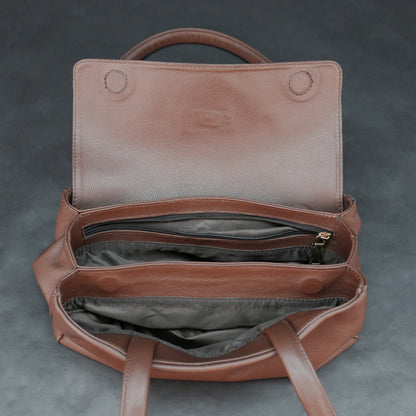 Brown cow Chelsea leather bag with straps, two compartments, and zipper pocket.