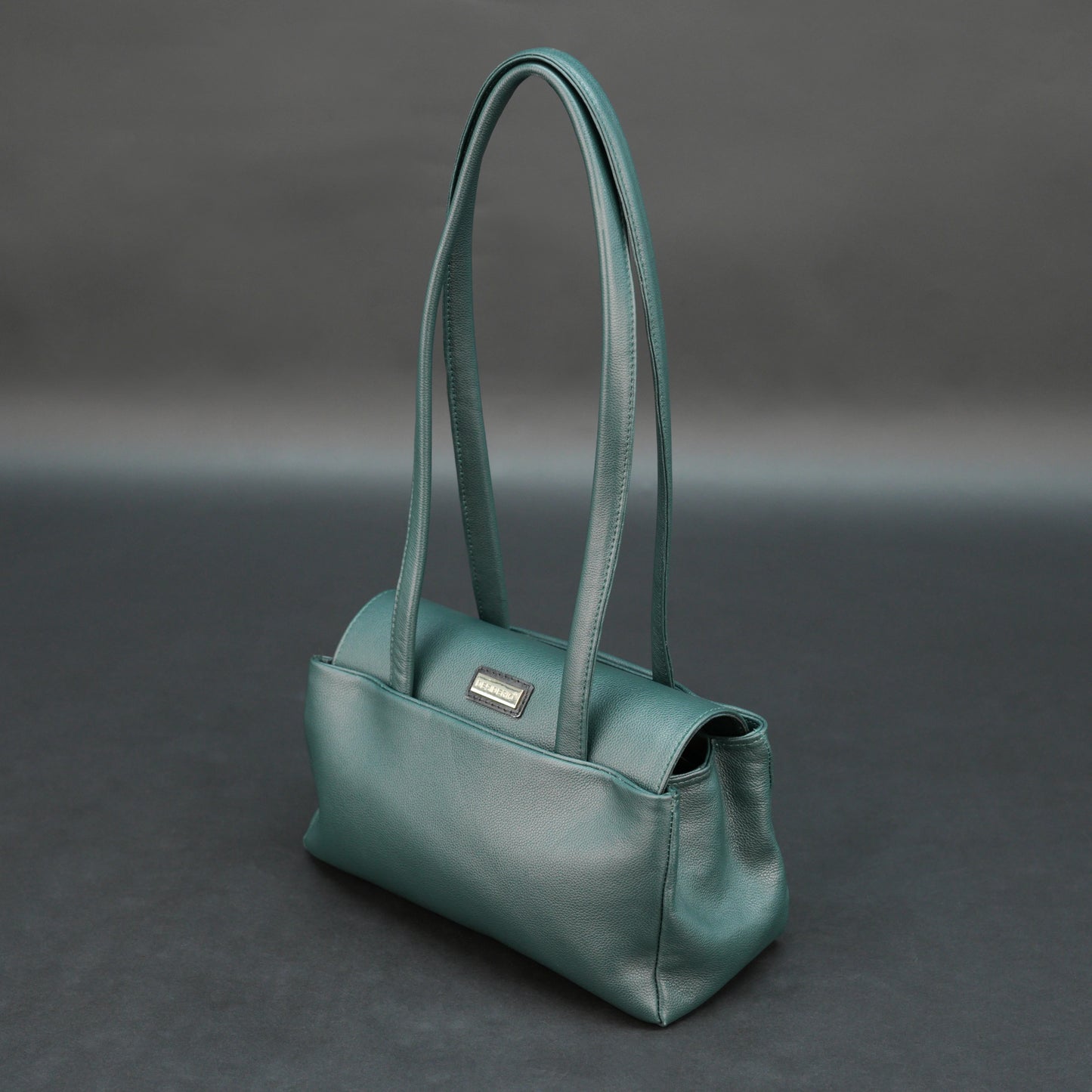 Deep jade cow Bamie leather bag with straps, dual compartments, and zipper pocket.