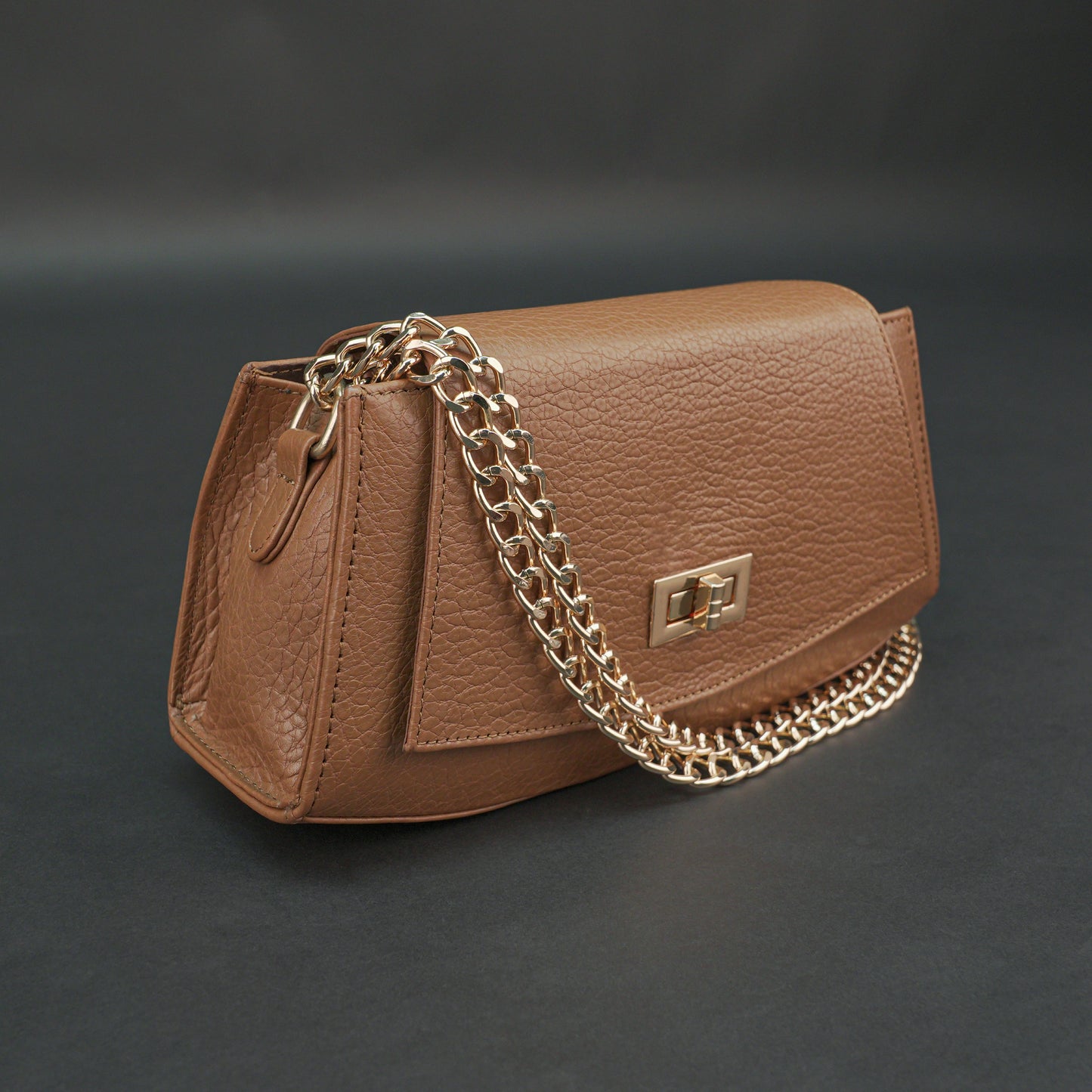Tan leather handbag with chain and zipper.