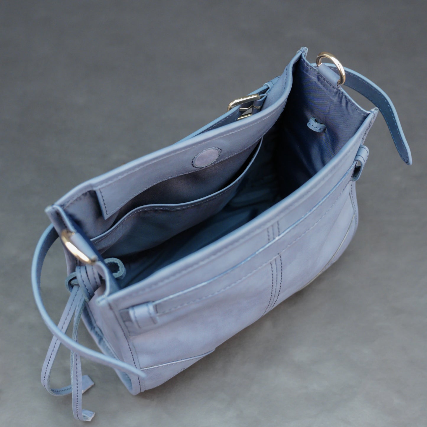 Light blue cow leather bag with shoulder strap, main compartment, and inner pockets.