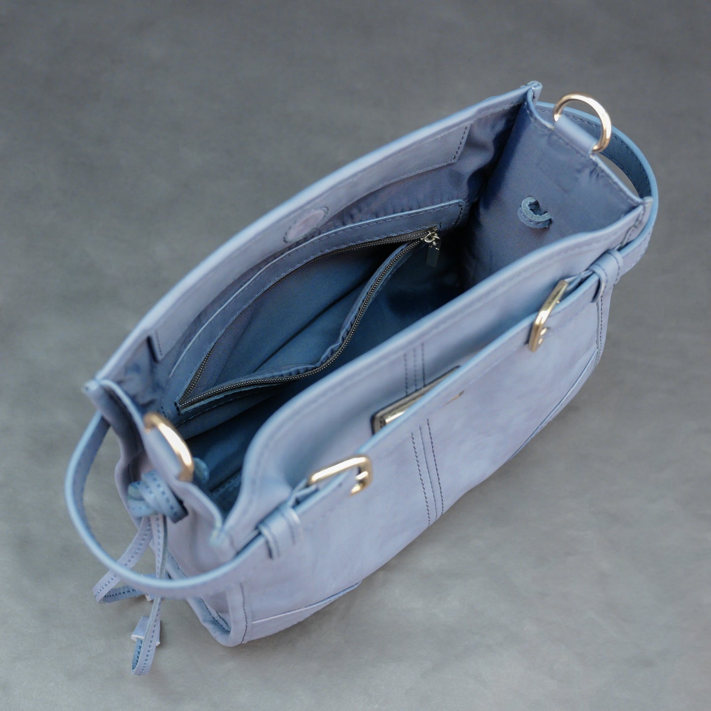 Light blue cow leather bag with shoulder strap, main compartment, and inner pockets.