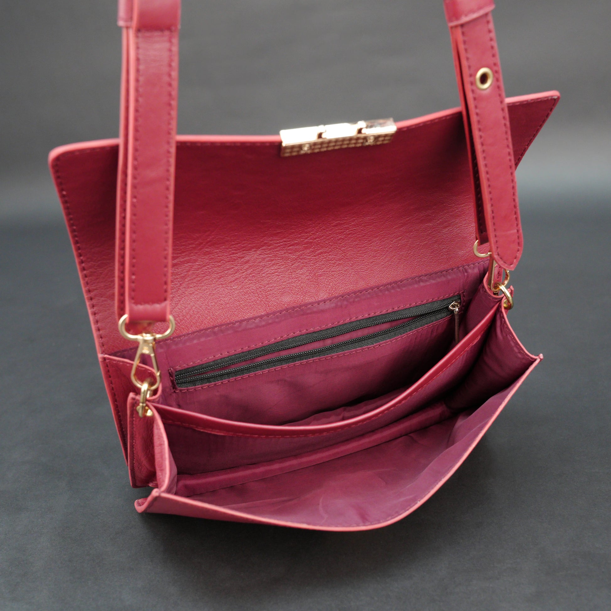 Maroon sheep leather bag with chain strap and zipper pocket.