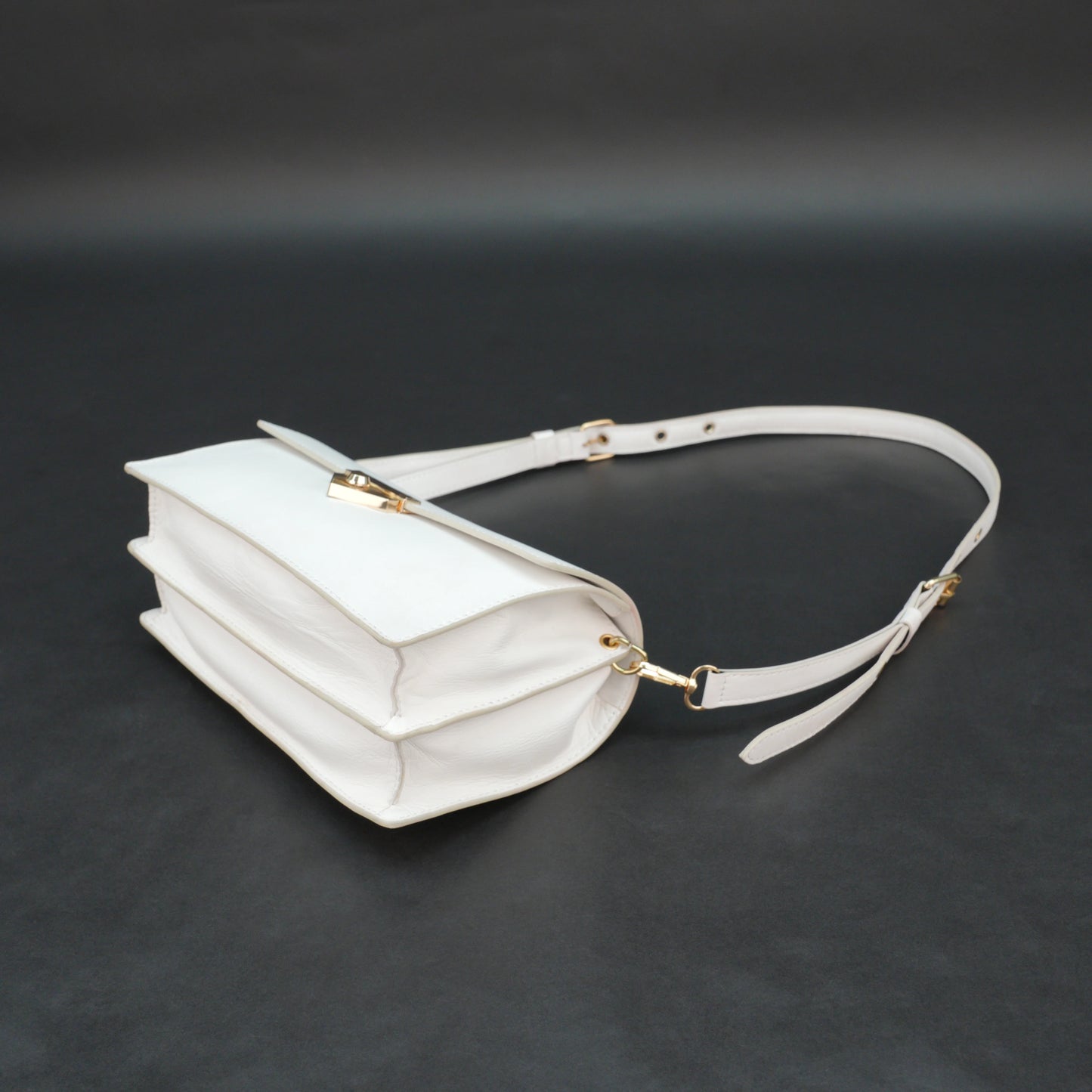 White sheep leather bag with chain strap, two compartments, and zipper pocket.