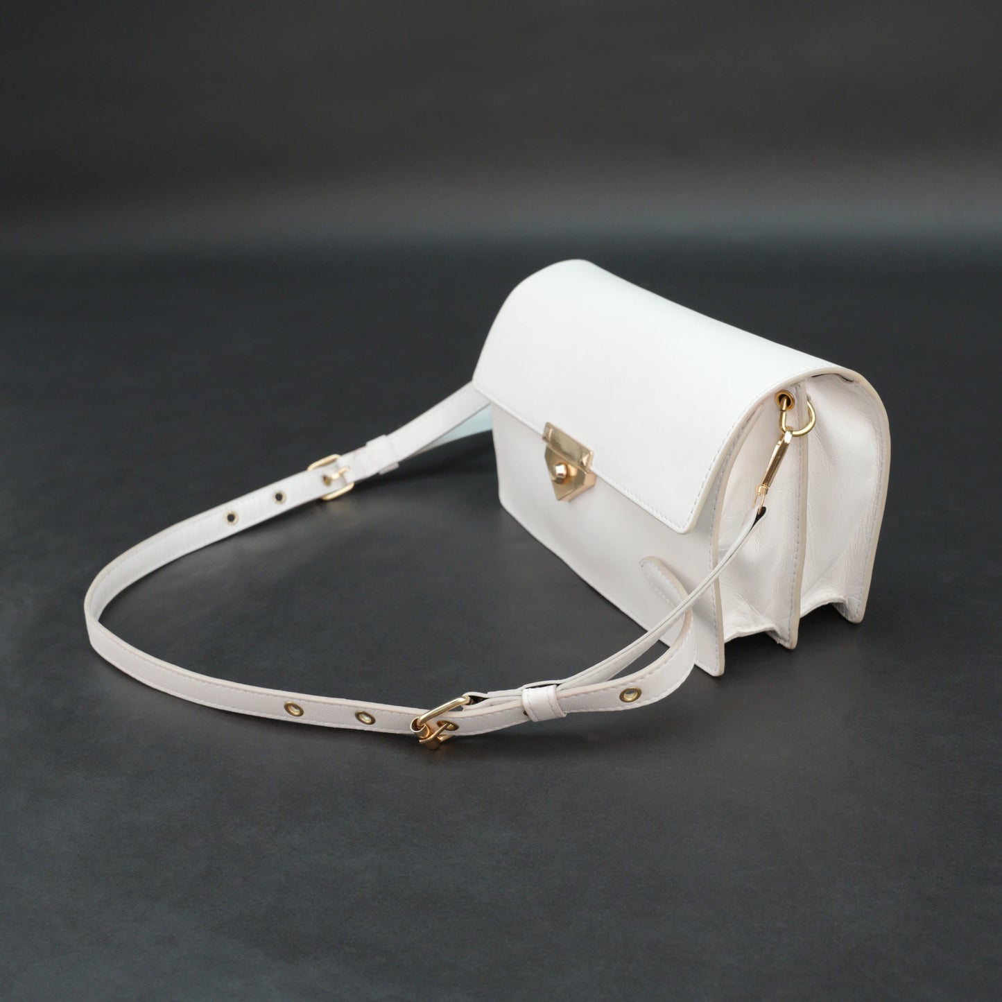 White sheep leather bag with chain strap, two compartments, and zipper pocket.