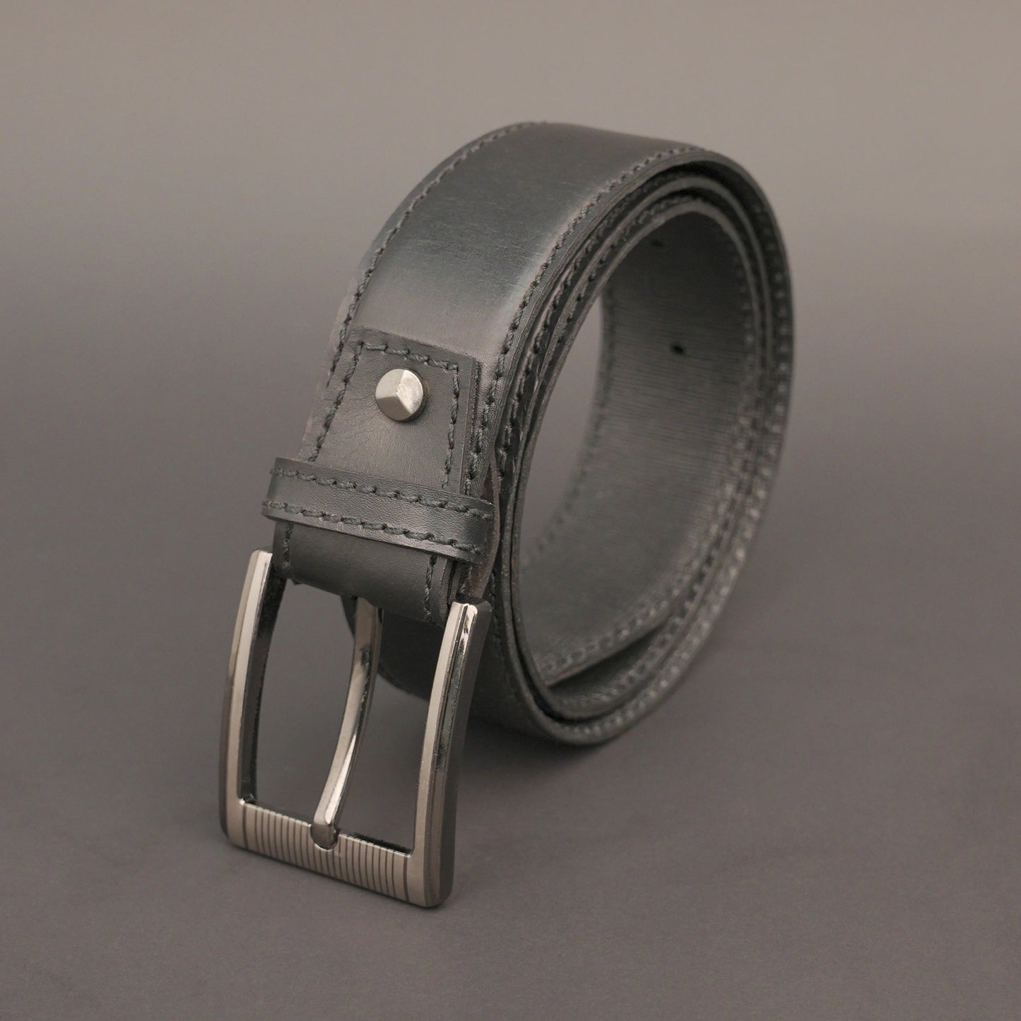 Premium leather belt with solid one-piece construction, charcoal metal buckle, durable, adjustable, stylish for jeans and dress wear