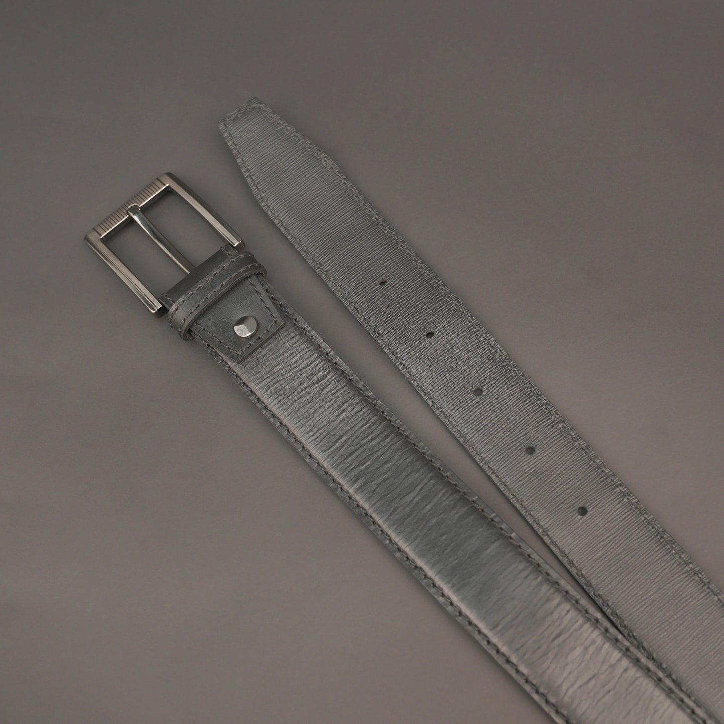 Premium leather belt with solid one-piece construction, charcoal metal buckle, durable, adjustable, stylish for jeans and dress wear