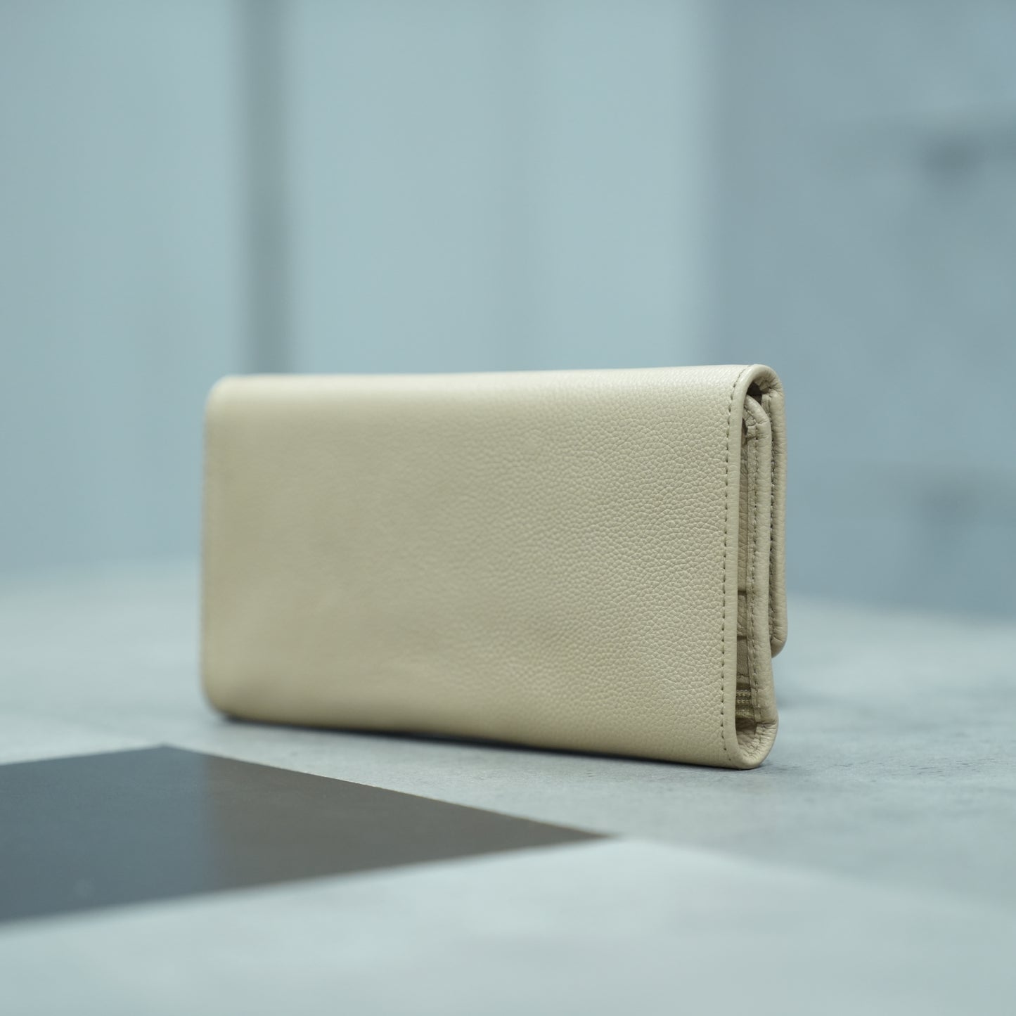 Beige leather clutch with two open pockets, one zip pocket, and eleven card slots