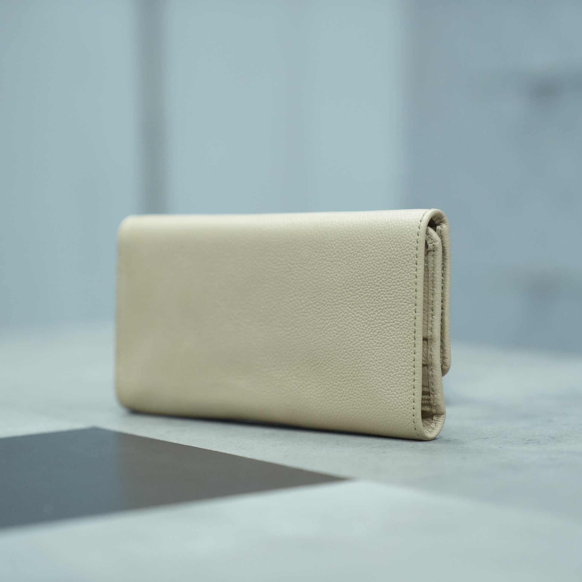 Beige leather clutch with two open pockets, one zip pocket, and eleven card slots
