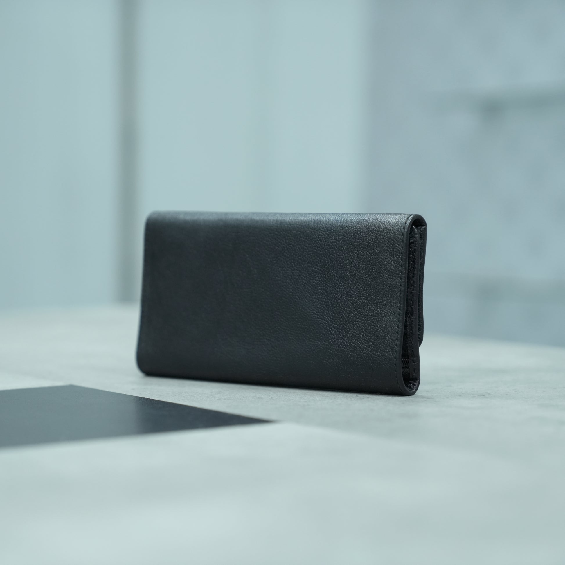 Black leather clutch with two open pockets, one zip pocket, and eleven card slots for organized storage