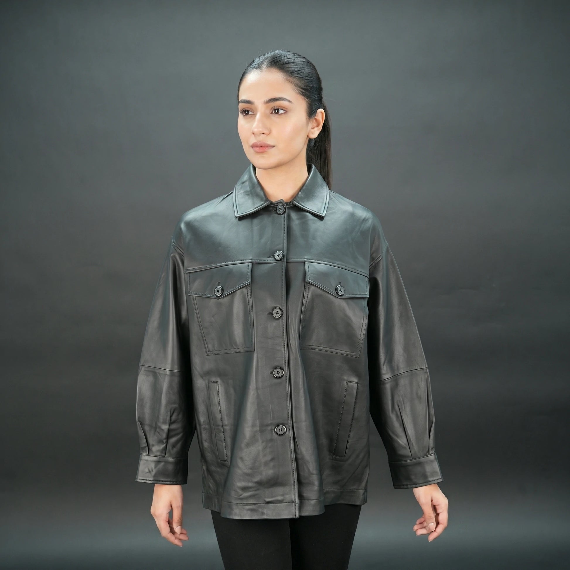 Black leather jacket with button closure, flap pockets, and relaxed fit.