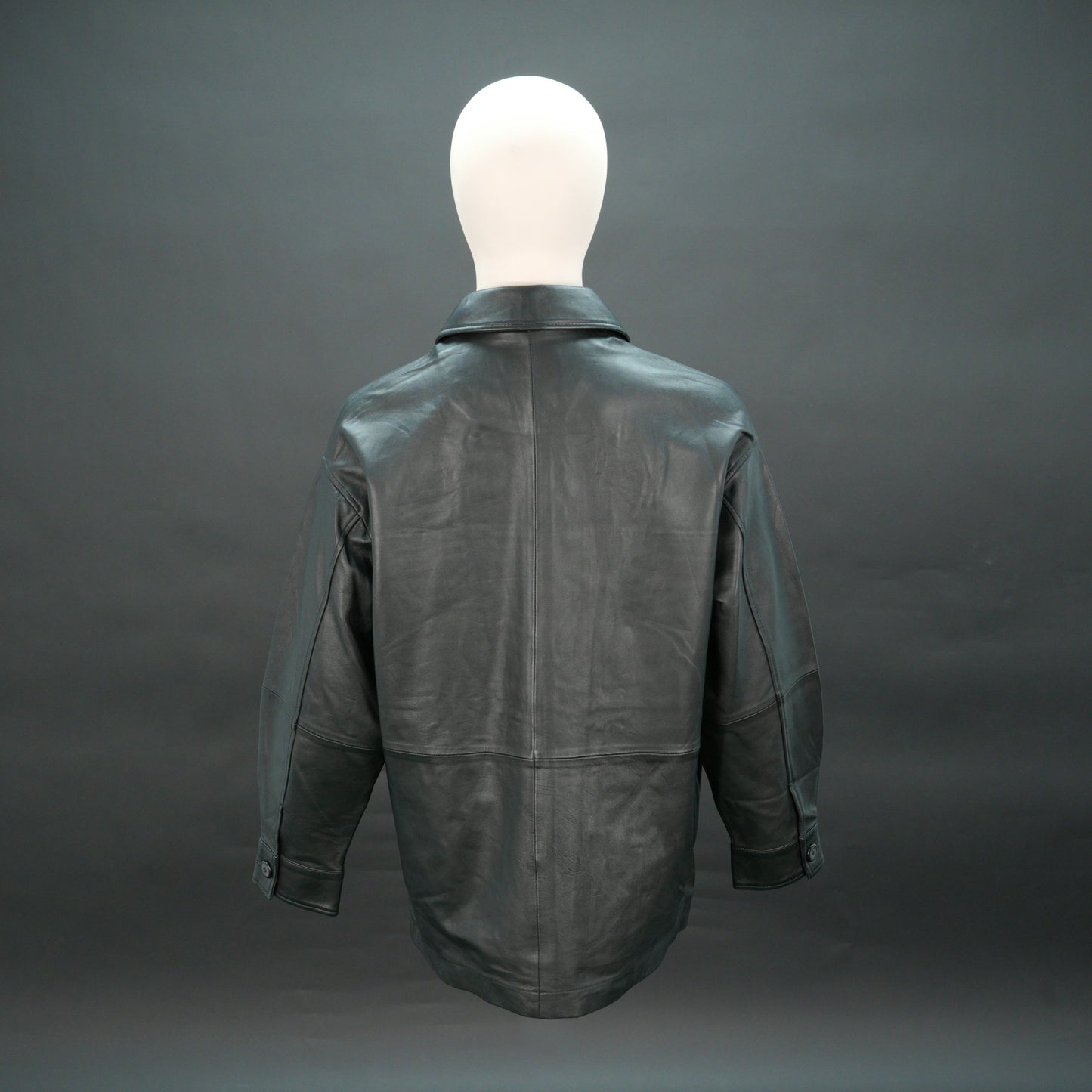 Black leather jacket with button closure, flap pockets, and relaxed fit.